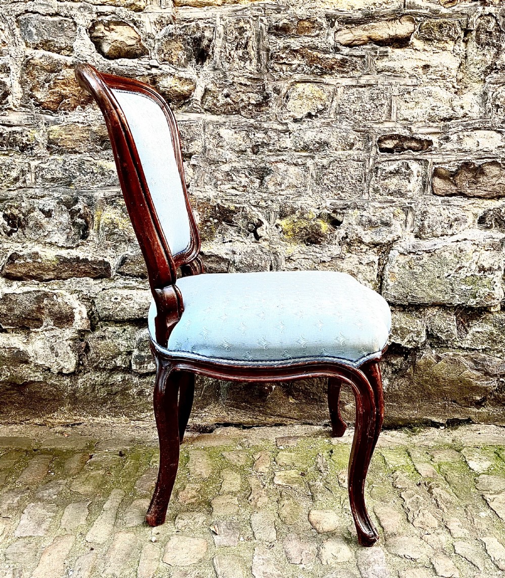 A set of four mid-19th century Louis XV style dining chairs featuring carved dark wood frames, cabriole legs, and light blue patterned fabric upholstery. View VI