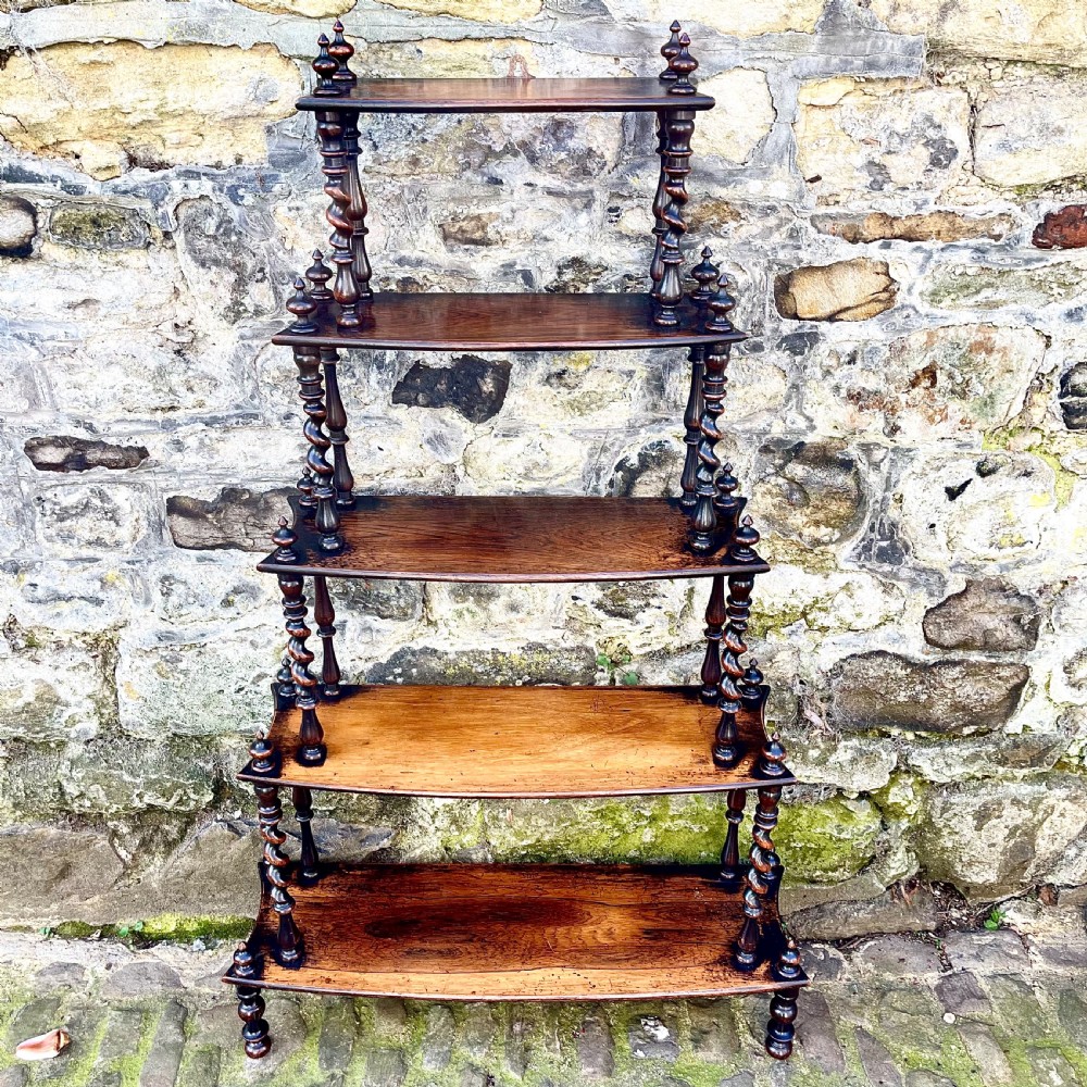 An early Victorian rosewood tiered shelf unit featuring five graduated tiers supported by turned barley twist columns and topped with finials. View II