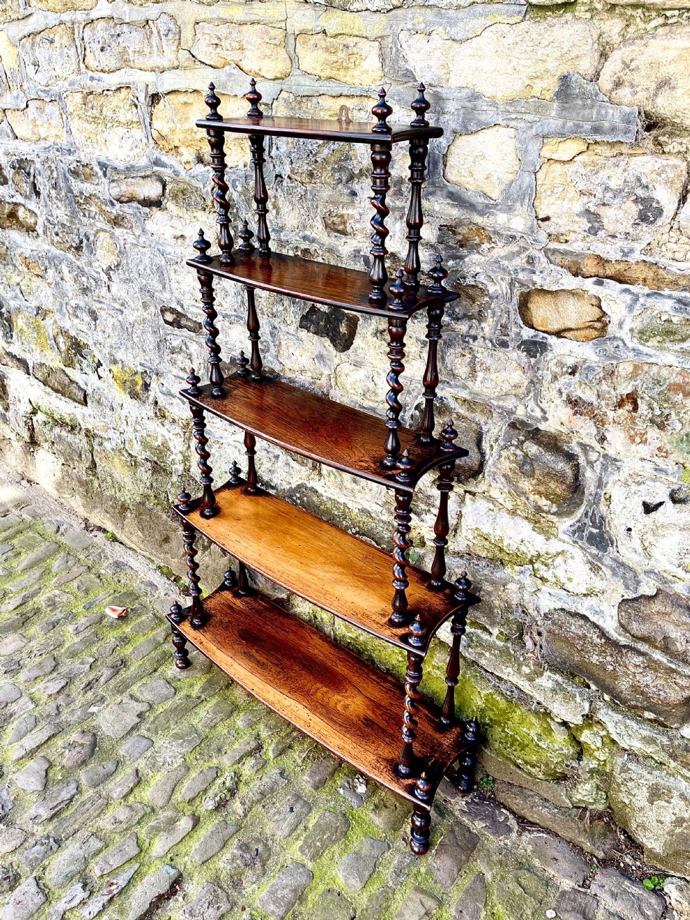 An early Victorian rosewood tiered shelf unit featuring five graduated tiers supported by turned barley twist columns and topped with finials. View IV