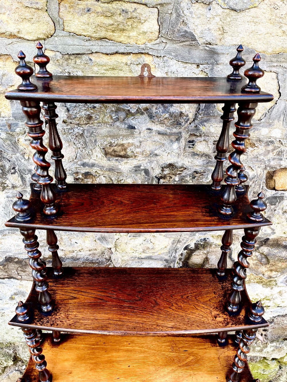 An early Victorian rosewood tiered shelf unit featuring five graduated tiers supported by turned barley twist columns and topped with finials. View V