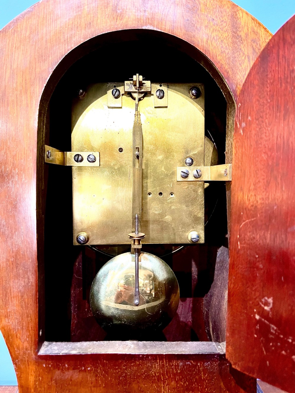 A late 19th-century mahogany balloon clock featuring satinwood marquetry inlay of floral scrolls, a circular dial with Roman numerals, and brass feet. View IV