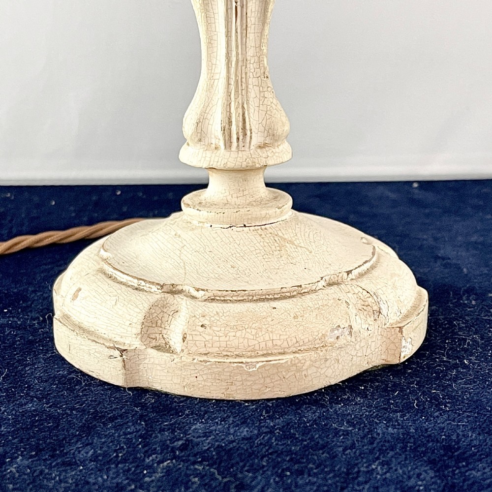 An early 20th century turned wood candlestick table lamp featuring a distressed cream painted finish and a brass bulb fitting. View II