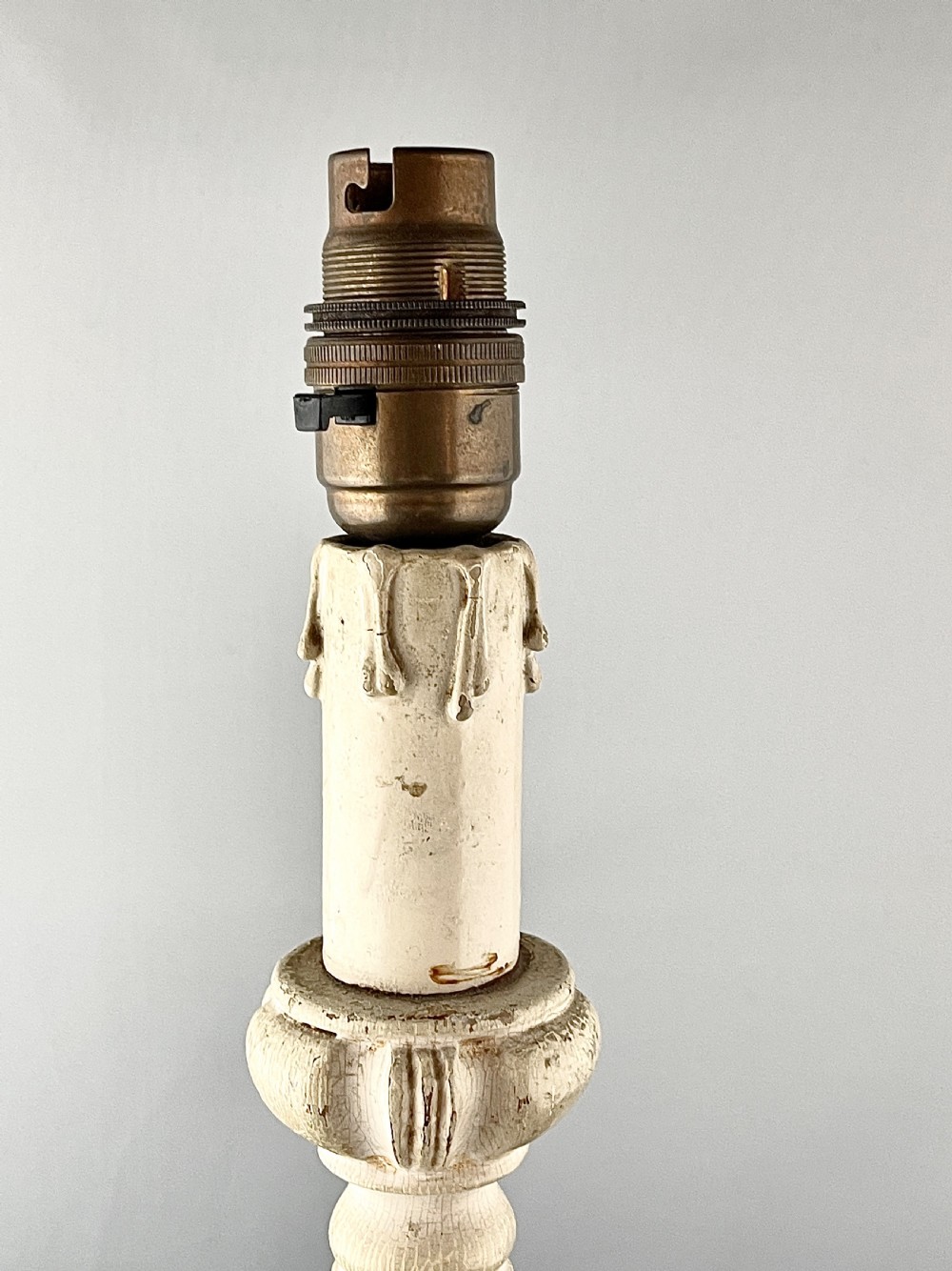 An early 20th century turned wood candlestick table lamp featuring a distressed cream painted finish and a brass bulb fitting. View III