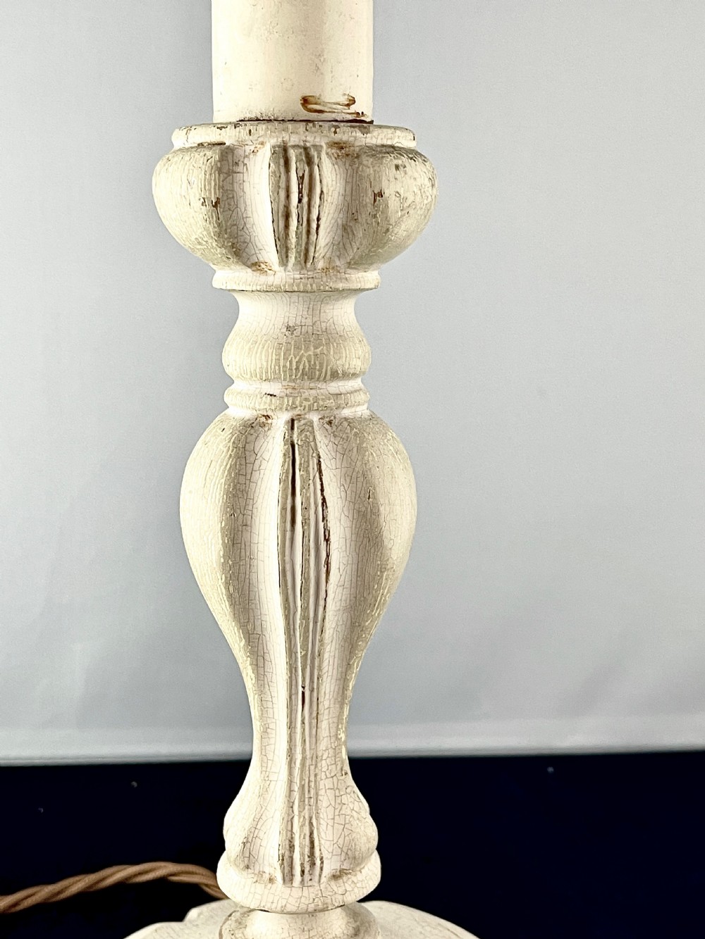 An early 20th century turned wood candlestick table lamp featuring a distressed cream painted finish and a brass bulb fitting. View IV