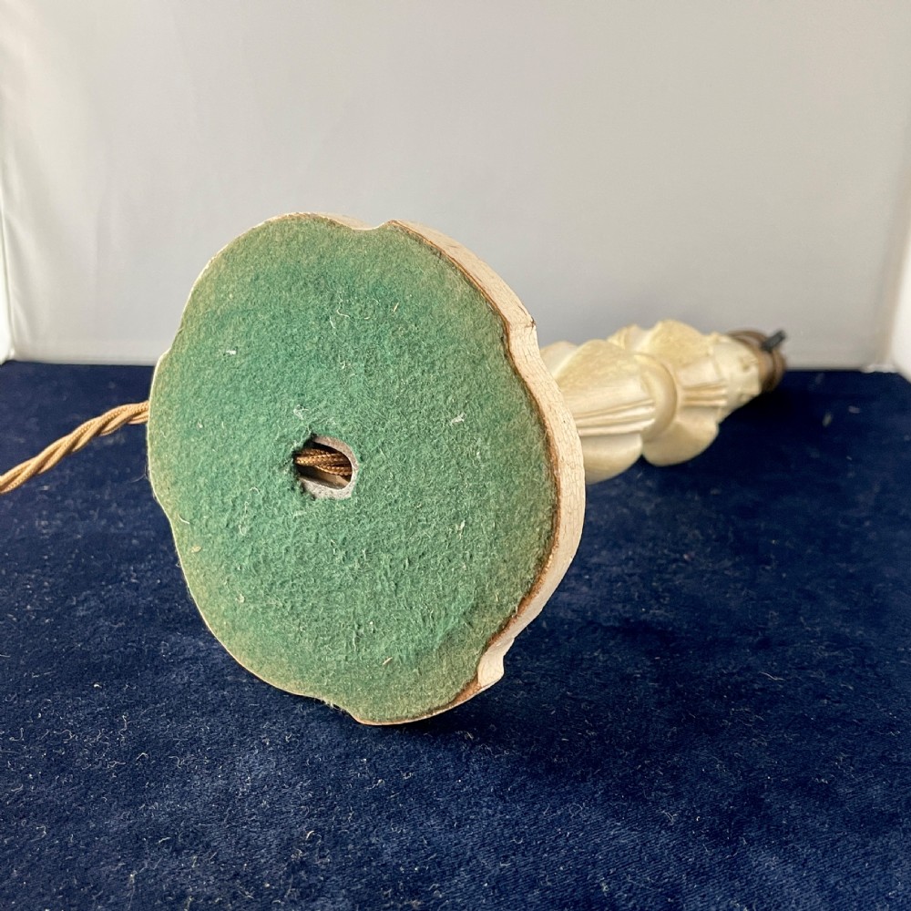An early 20th century turned wood candlestick table lamp featuring a distressed cream painted finish and a brass bulb fitting. View V