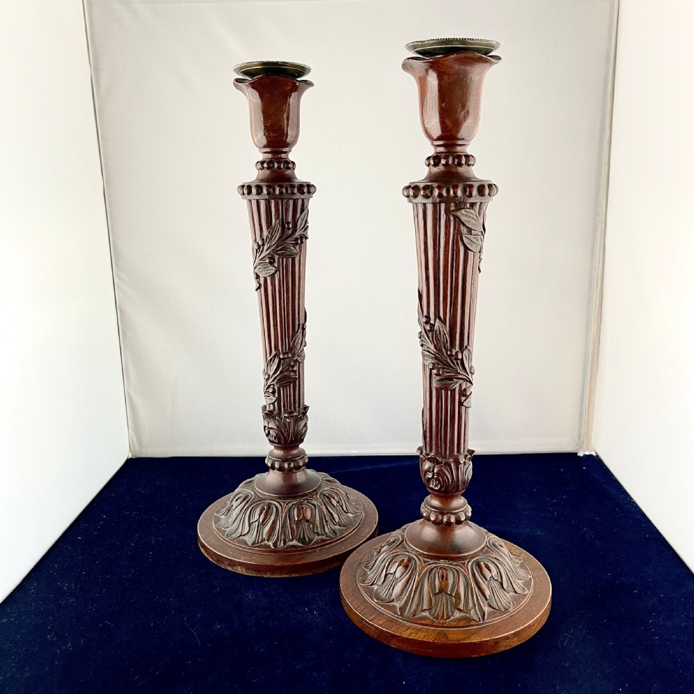 A pair of carved mahogany wooden candlesticks featuring fluted columns, leaf motifs, and circular bases in the Louis XVI style. View II