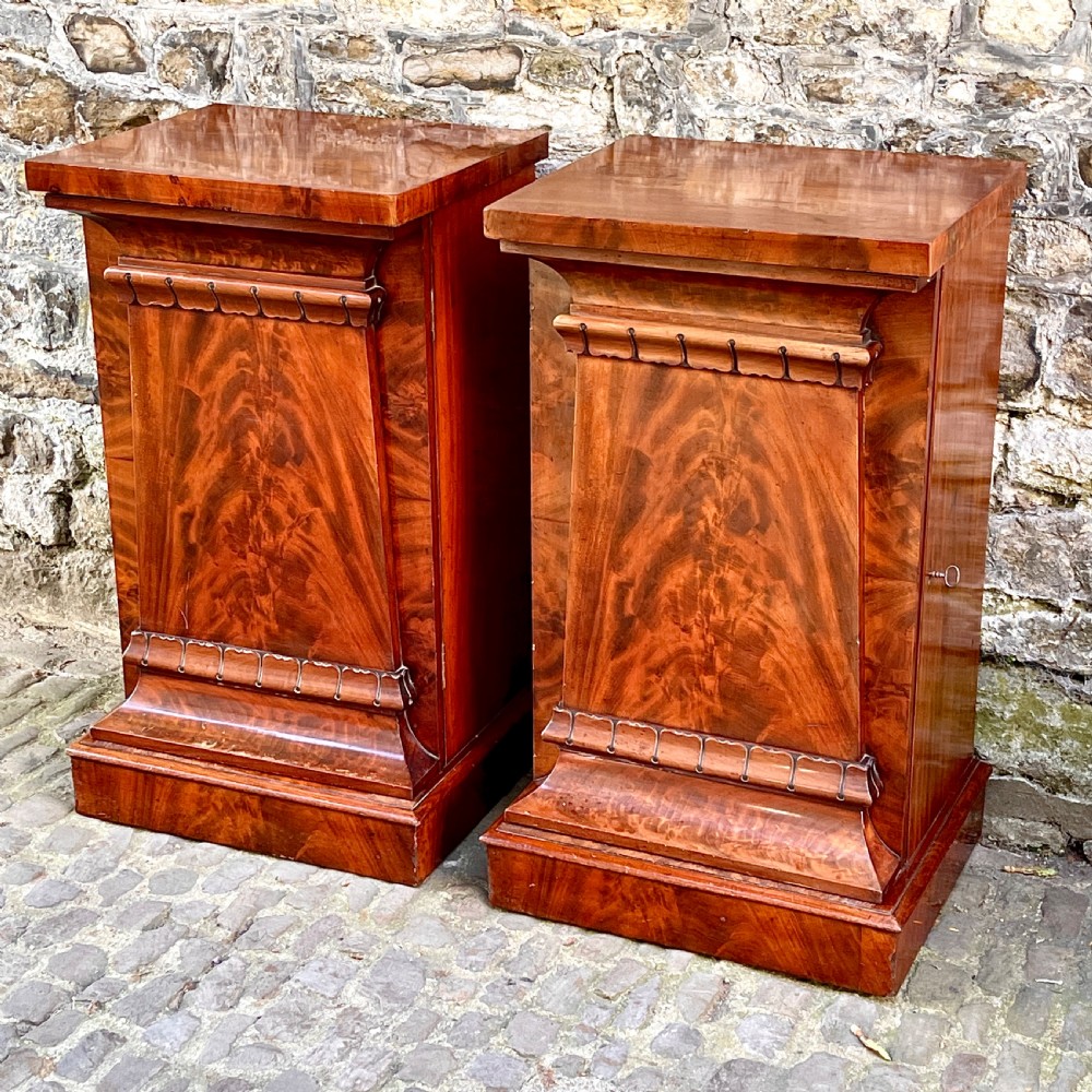 A pair of George IV flame mahogany pedestal cupboards featuring carved mouldings and plinth bases. View IV