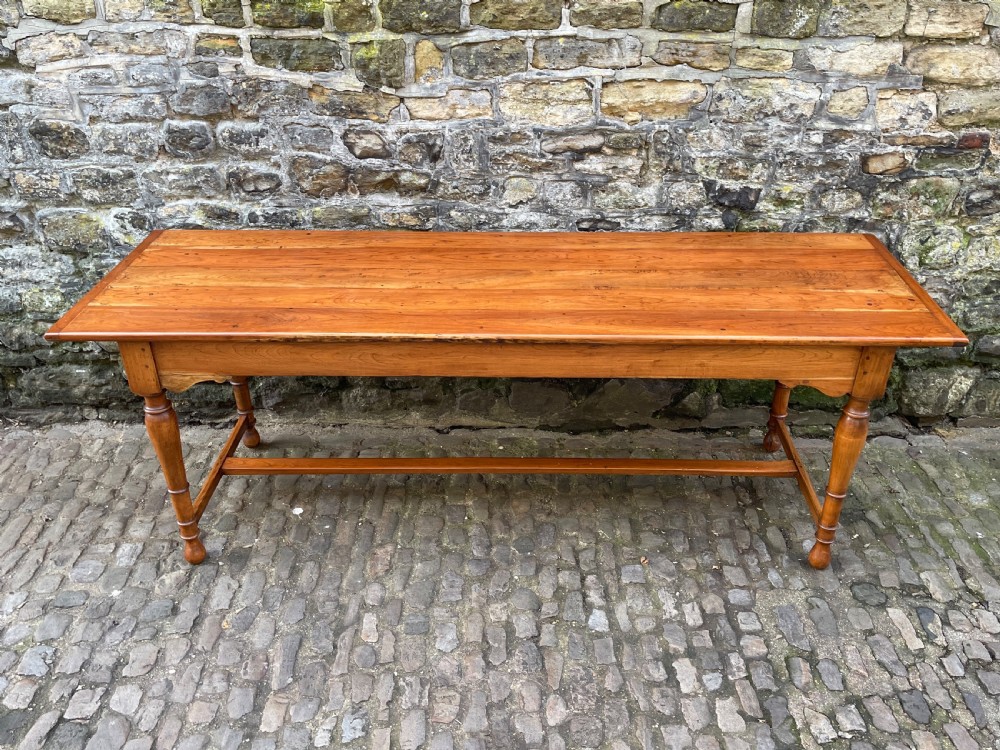 A long mid-Victorian walnut farmhouse dining table with turned legs connected by a low stretcher base.