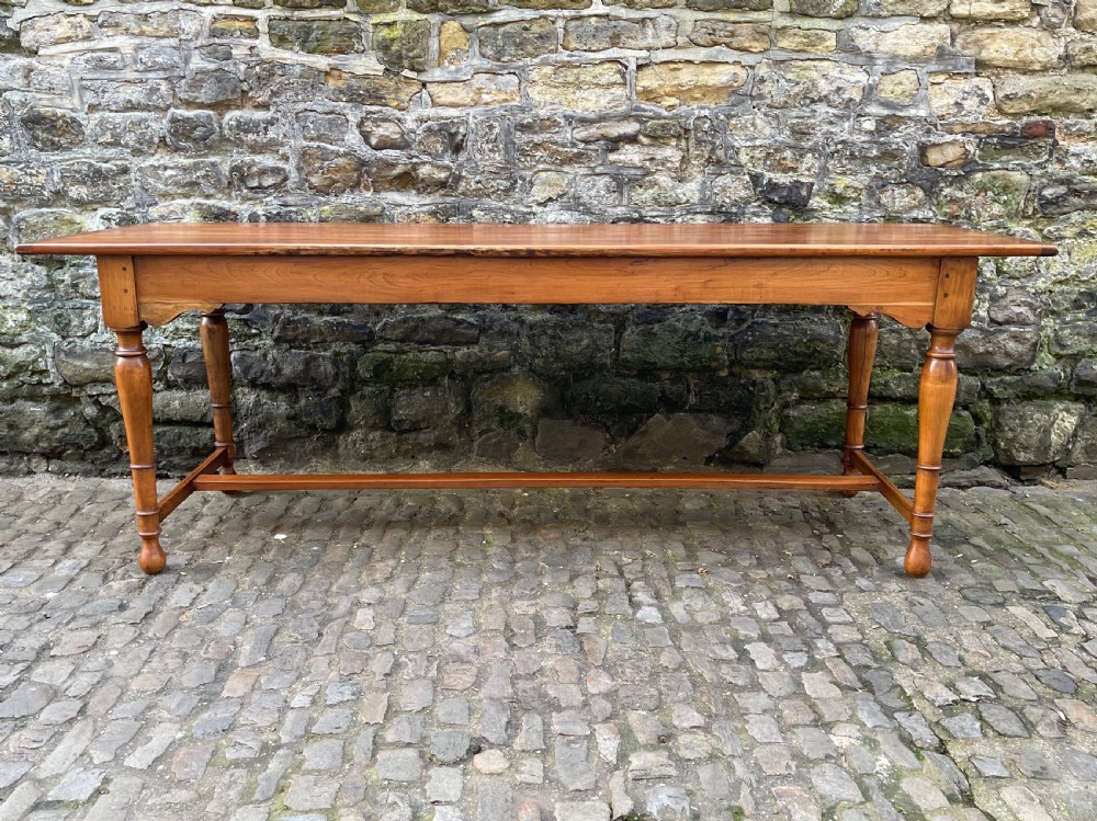 A long mid-Victorian walnut farmhouse dining table with turned legs connected by a low stretcher base. View II