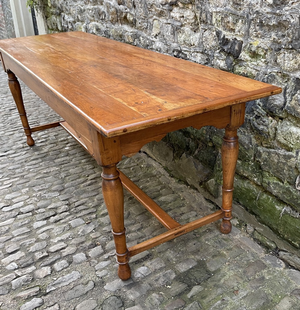 A long mid-Victorian walnut farmhouse dining table with turned legs connected by a low stretcher base. View III