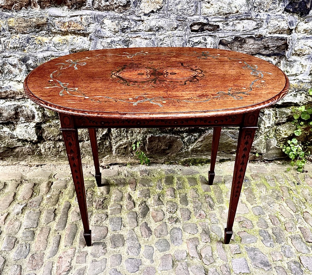 An oval wooden occasional table featuring hand-painted ribbon and floral garlands on the tabletop, supported by four tapered legs with linear details. View II
