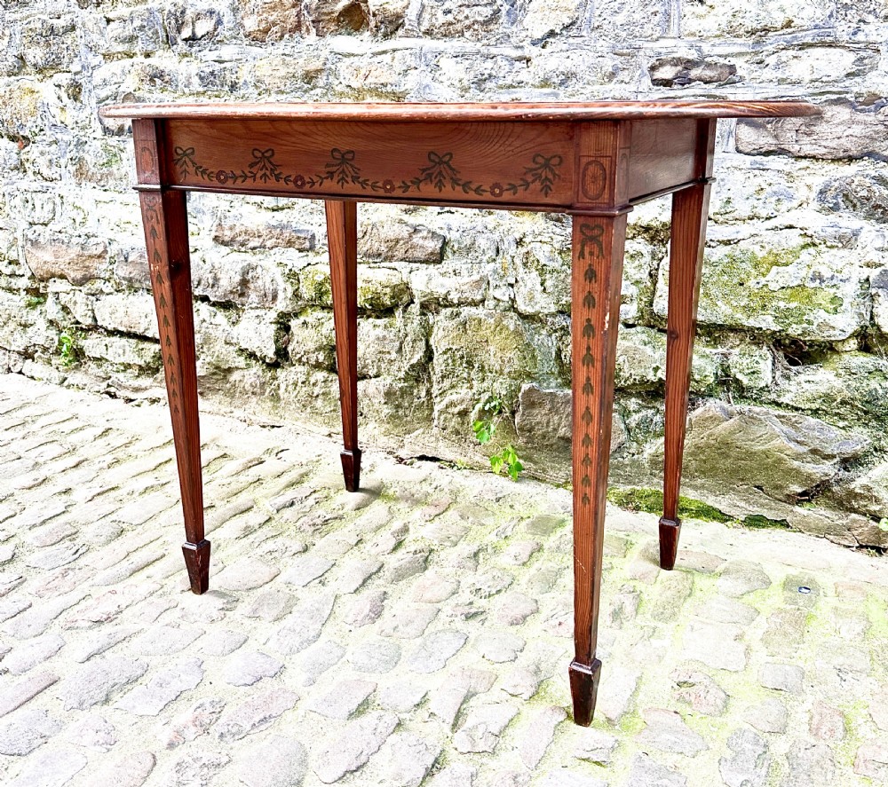 An oval wooden occasional table featuring hand-painted ribbon and floral garlands on the tabletop, supported by four tapered legs with linear details. View IV