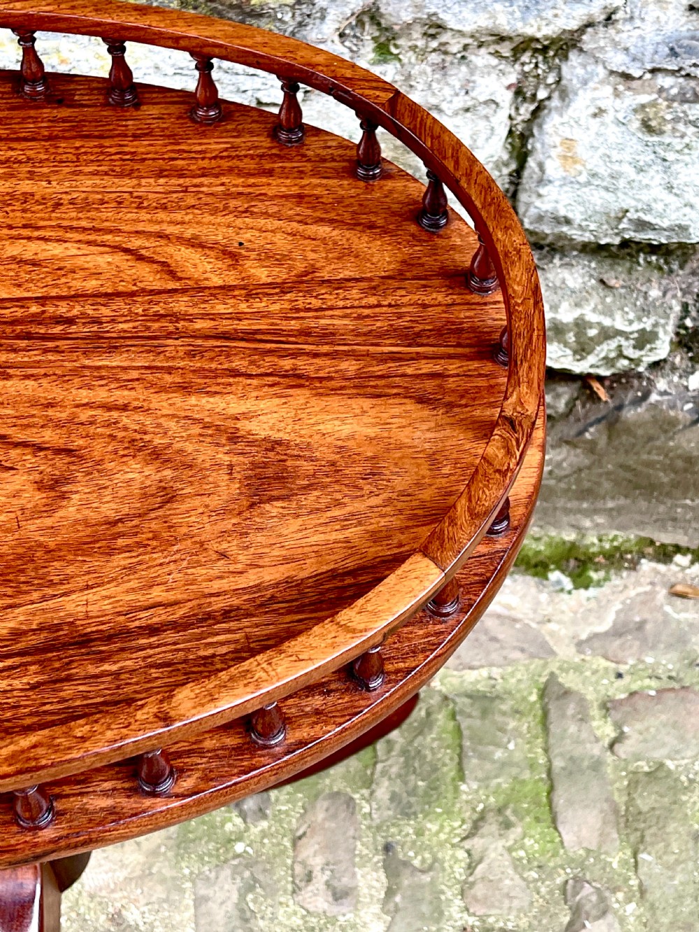 A late Victorian rosewood wine table featuring an oval top with a spindle gallery rail, raised on a central turned pedestal with tripod legs. View II