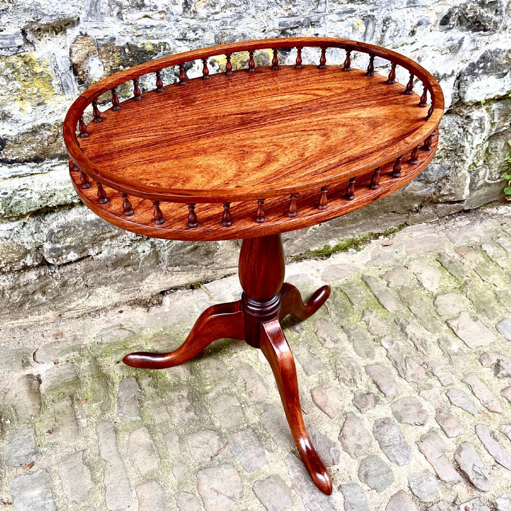 A late Victorian rosewood wine table featuring an oval top with a spindle gallery rail, raised on a central turned pedestal with tripod legs. View III