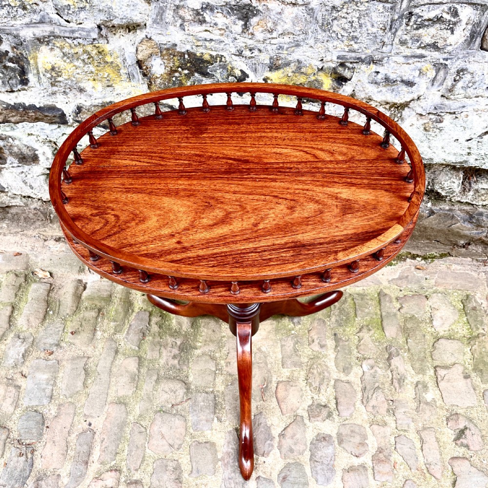 A late Victorian rosewood wine table featuring an oval top with a spindle gallery rail, raised on a central turned pedestal with tripod legs. View V