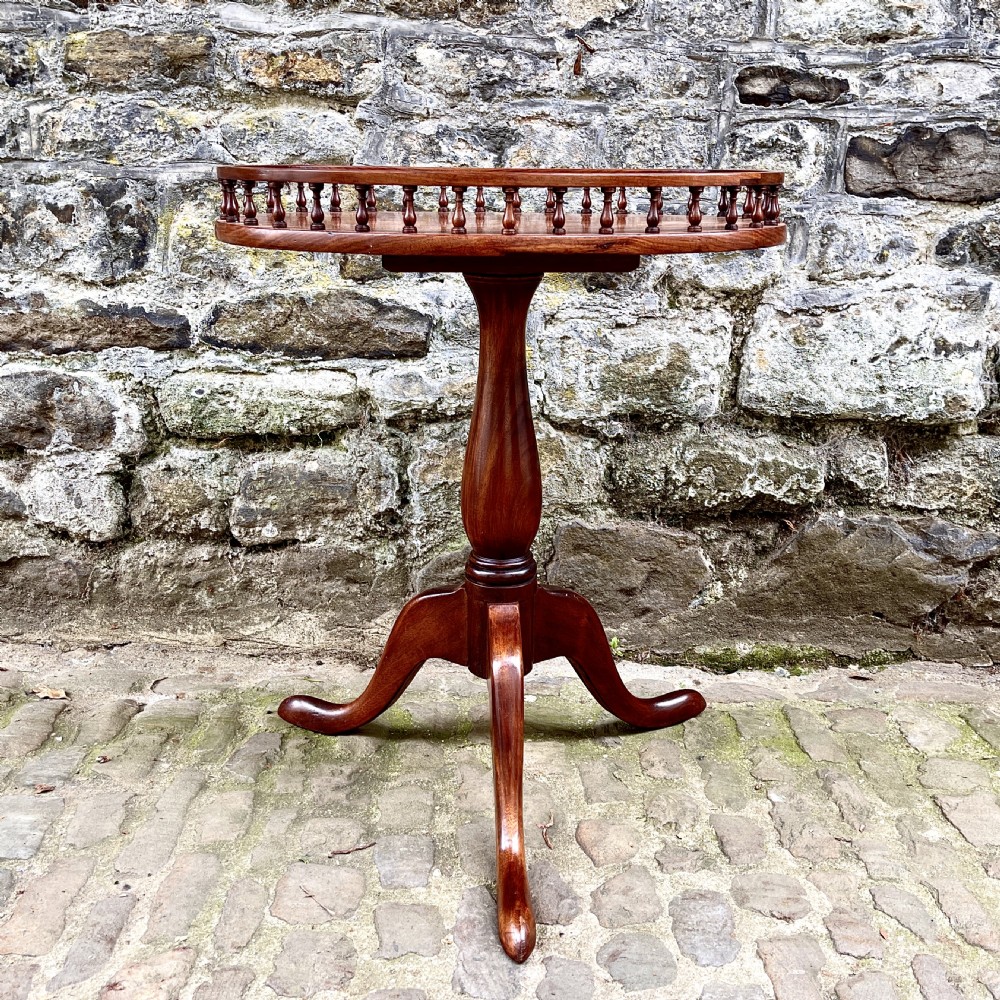 A late Victorian rosewood wine table featuring an oval top with a spindle gallery rail, raised on a central turned pedestal with tripod legs. View VI