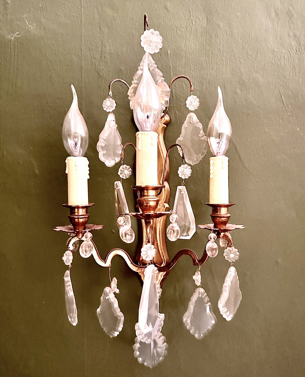 A Louis XV style three-arm gilt brass wall light embellished with cut crystal drops and floral rosette mounts. View II