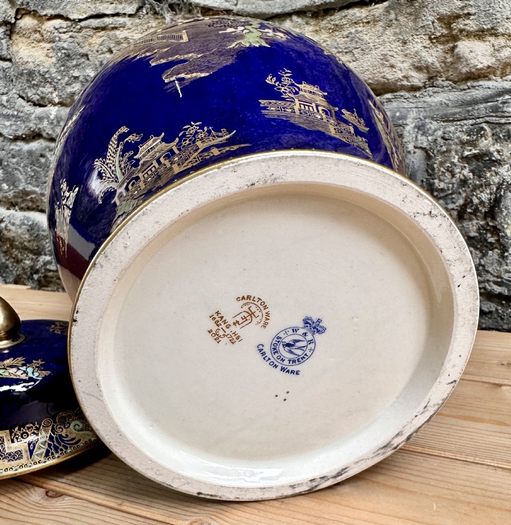 A pair of cobalt blue ceramic lidded vases decorated with gold gilt Chinoiserie pagoda scenes, set on dark circular ebonised wooden bases. View XIII