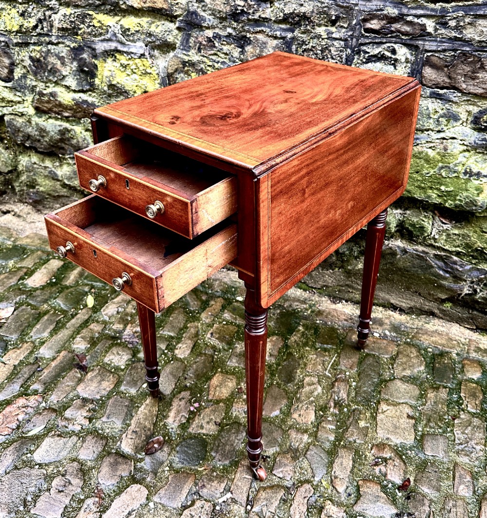 A Regency mahogany drop leaf side table featuring two drawers with brass knobs, boxwood string inlay, turned legs, and brass castors. View III