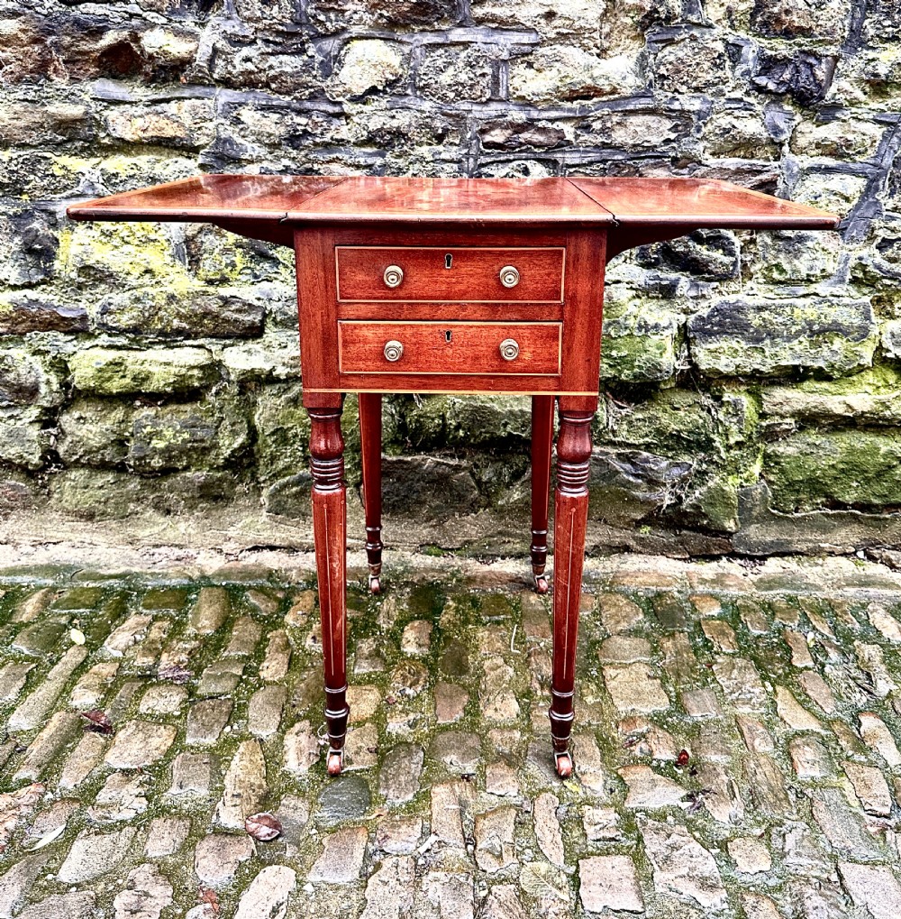 A Regency mahogany drop leaf side table featuring two drawers with brass knobs, boxwood string inlay, turned legs, and brass castors. View VIII