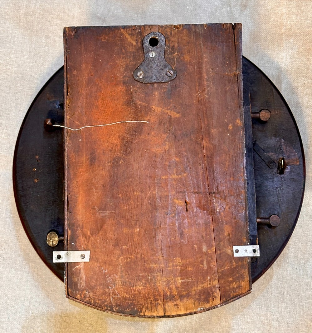 A circular George III mahogany wall clock featuring an engraved brass dial with Roman numerals and black steel hands. View IV
