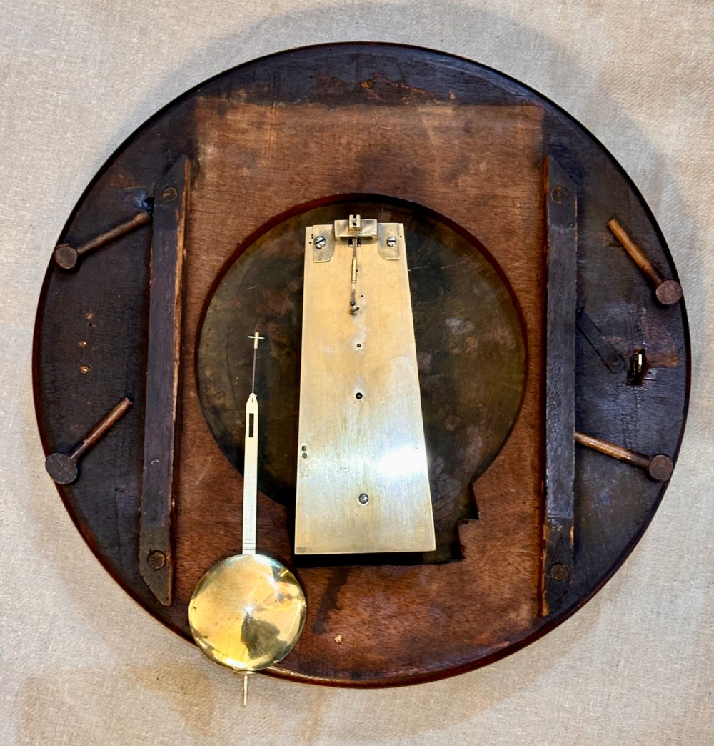 A circular George III mahogany wall clock featuring an engraved brass dial with Roman numerals and black steel hands. View V