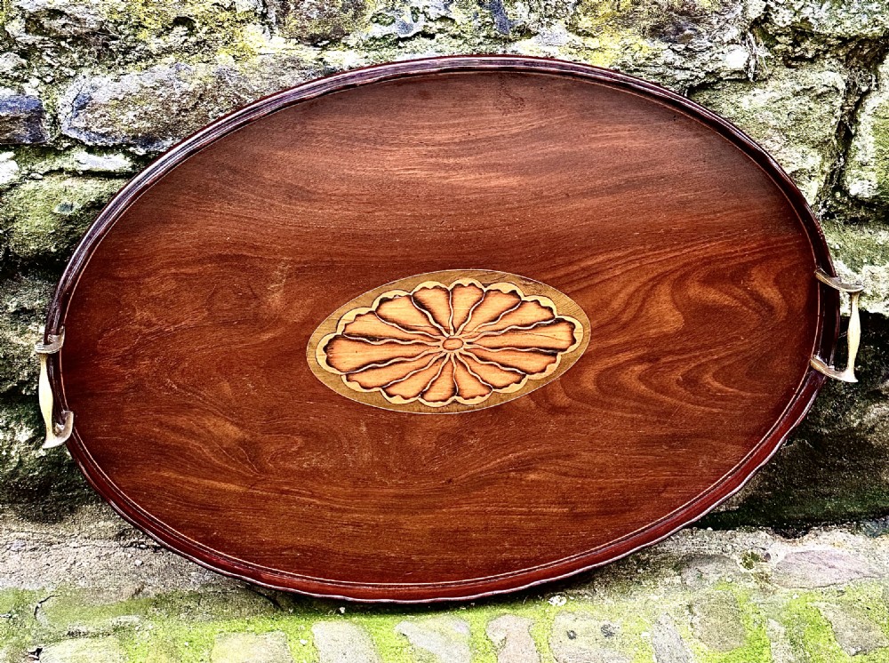 An oval George III mahogany serving tray featuring a central fan shell patera inlay and two brass carrying handles. View V