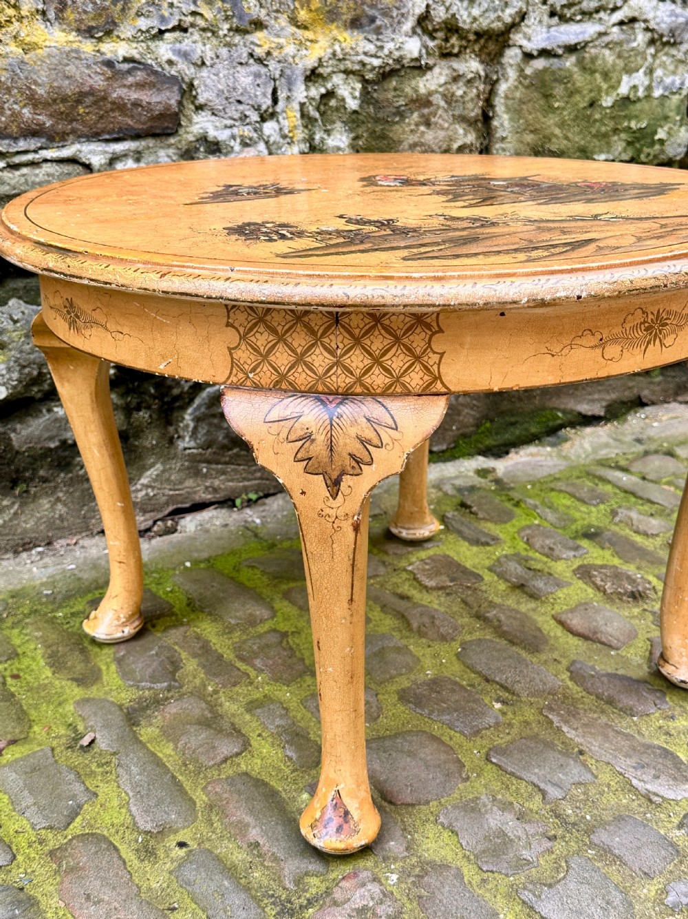 A low oval Chinoiserie coffee table featuring hand-painted East Asian landscape scenes on a cream lacquered top with cabriole legs. View V