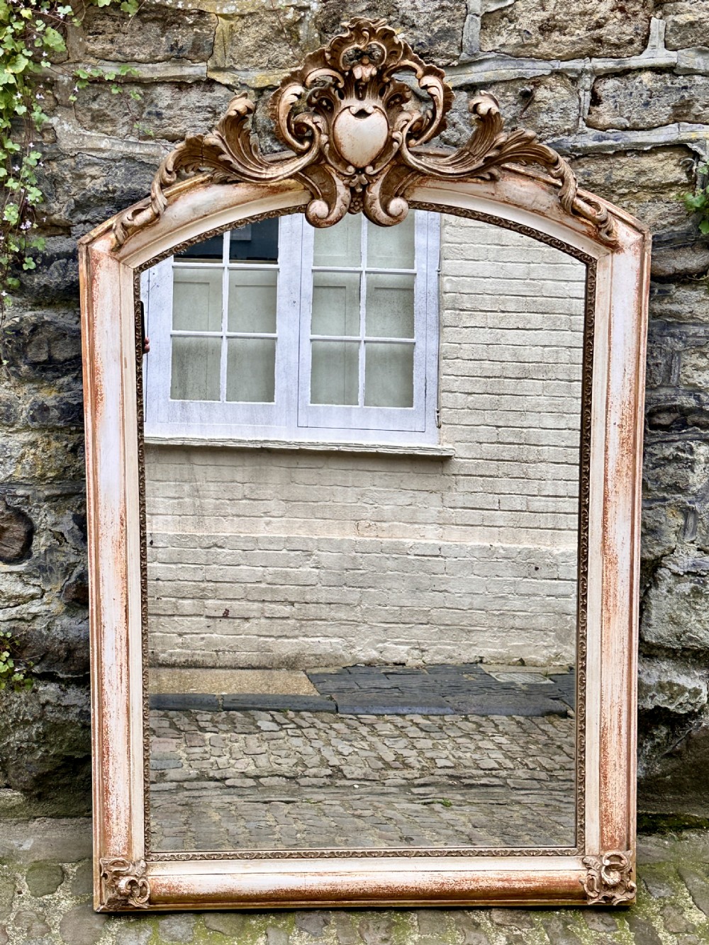 Mid 19th century arched French overmantel mirror with carved cartouche scroll cresting and a distressed cream and gold finish. View VI