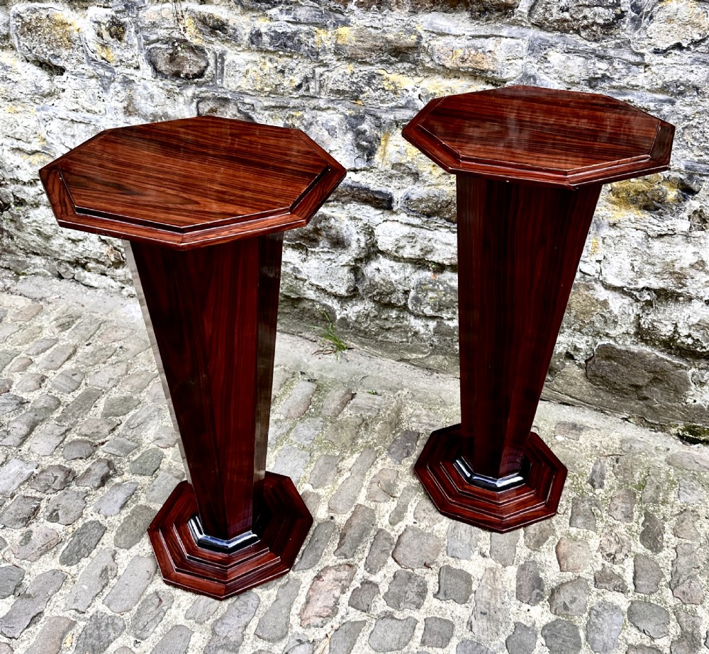 A pair of polished Art Deco wooden pedestal lamp tables with octagonal tops, faceted tapering columns, and stepped bases. View IX