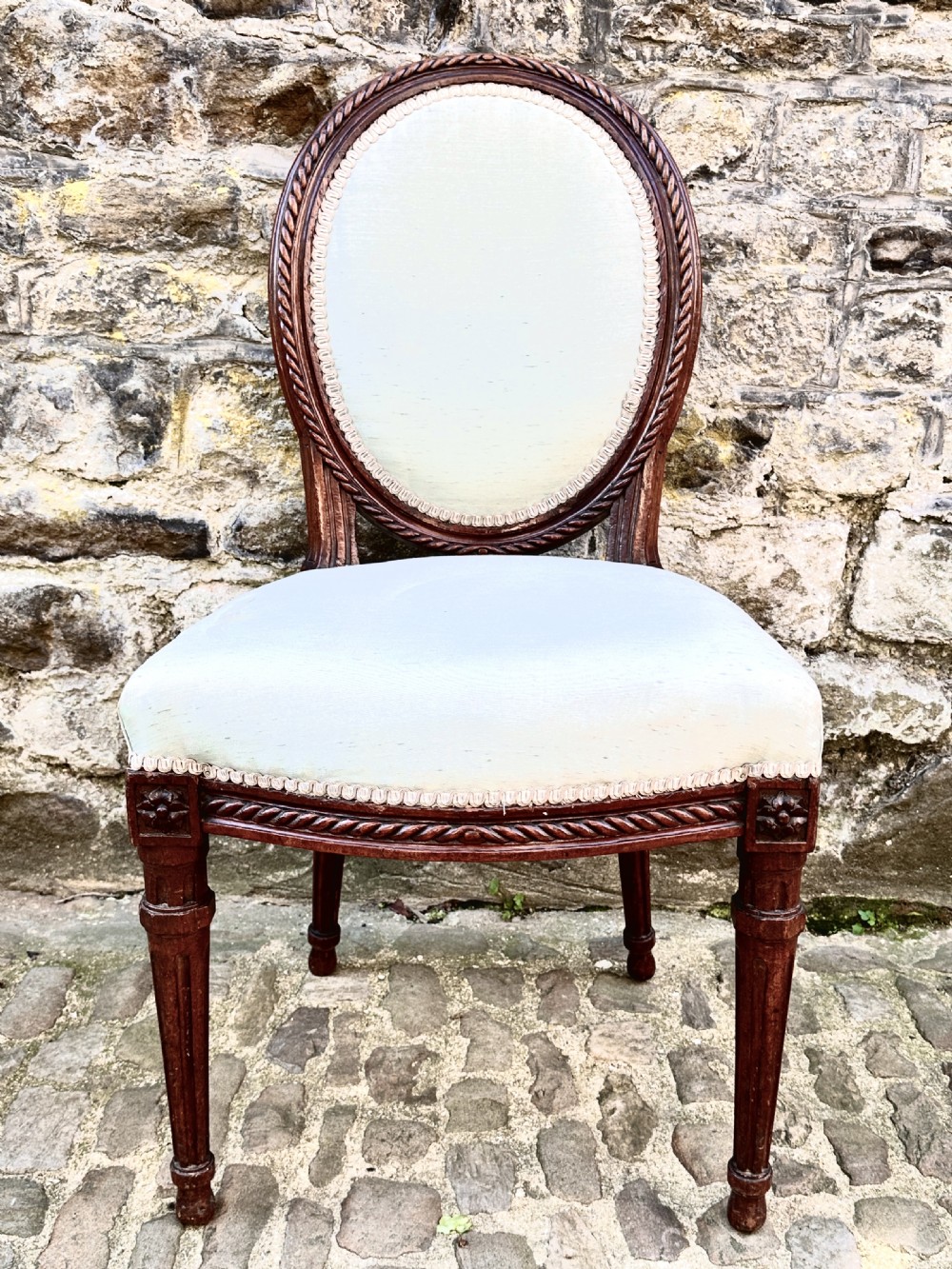 A set of four George III mahogany side chairs with oval upholstered backs, rope-twist carved borders, and fluted turned legs. View III
