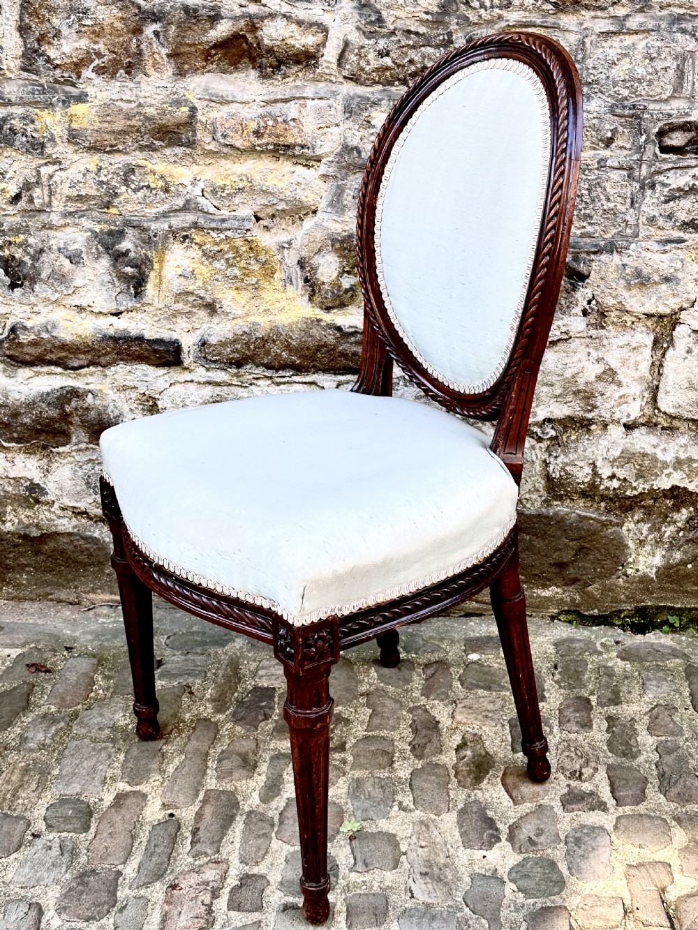 A set of four George III mahogany side chairs with oval upholstered backs, rope-twist carved borders, and fluted turned legs. View VI