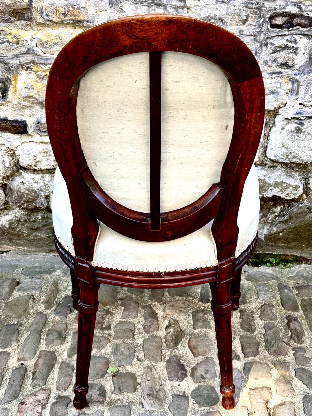 A set of four George III mahogany side chairs with oval upholstered backs, rope-twist carved borders, and fluted turned legs. View VII