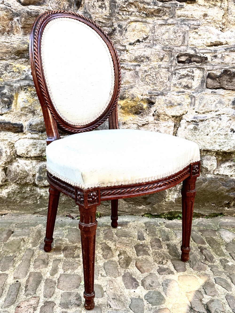 A set of four George III mahogany side chairs with oval upholstered backs, rope-twist carved borders, and fluted turned legs. View IX