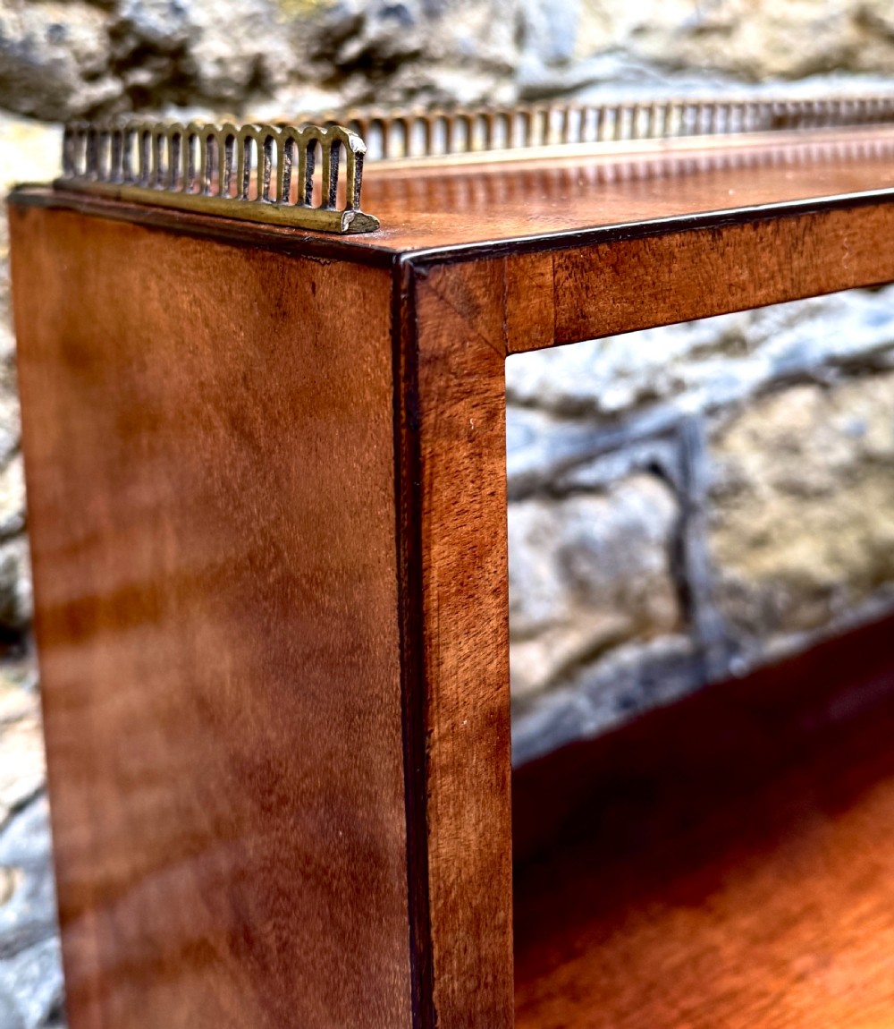 A George III mahogany chiffonier featuring a top open shelf unit with three small drawers above a two-drawer base cabinet with panelled doors and curved feet. View III