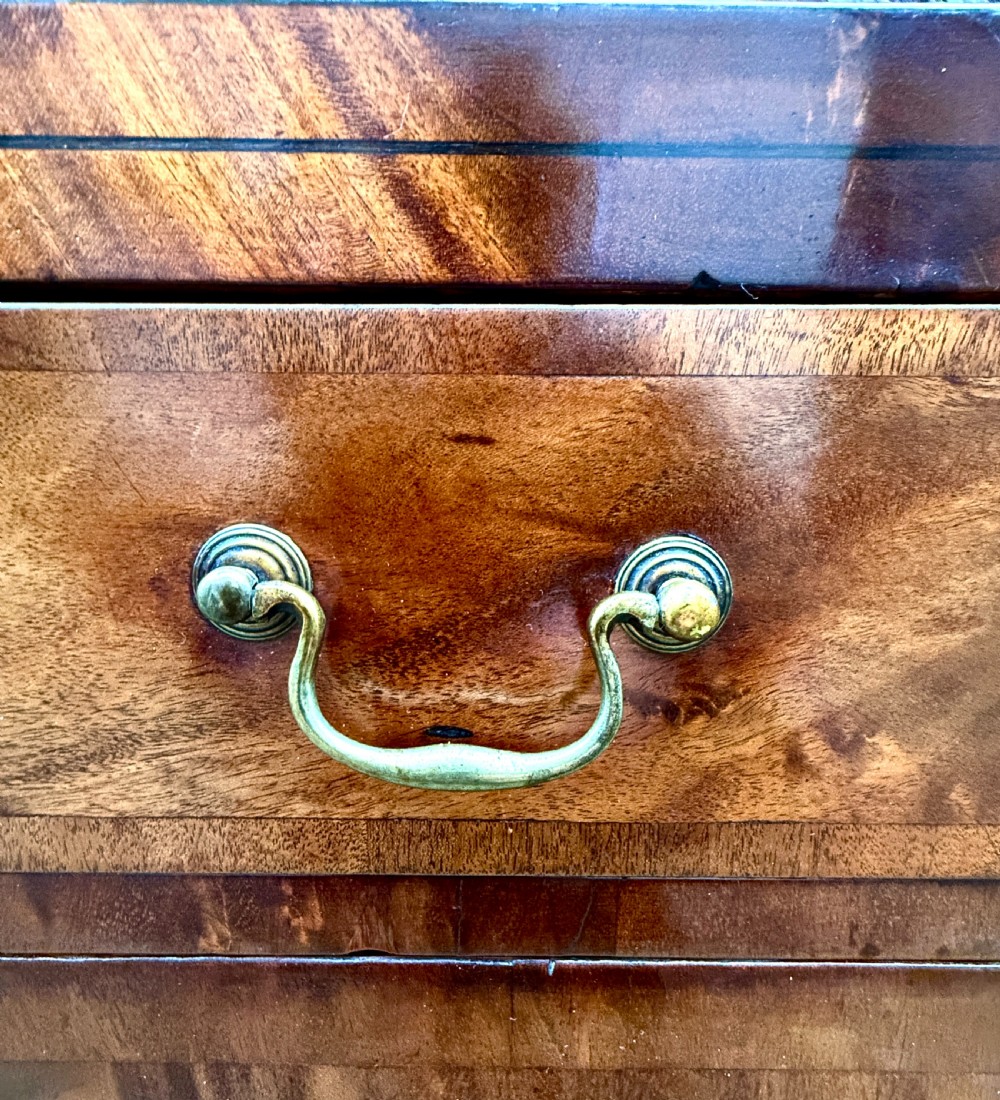 A George III mahogany chiffonier featuring a top open shelf unit with three small drawers above a two-drawer base cabinet with panelled doors and curved feet. View V