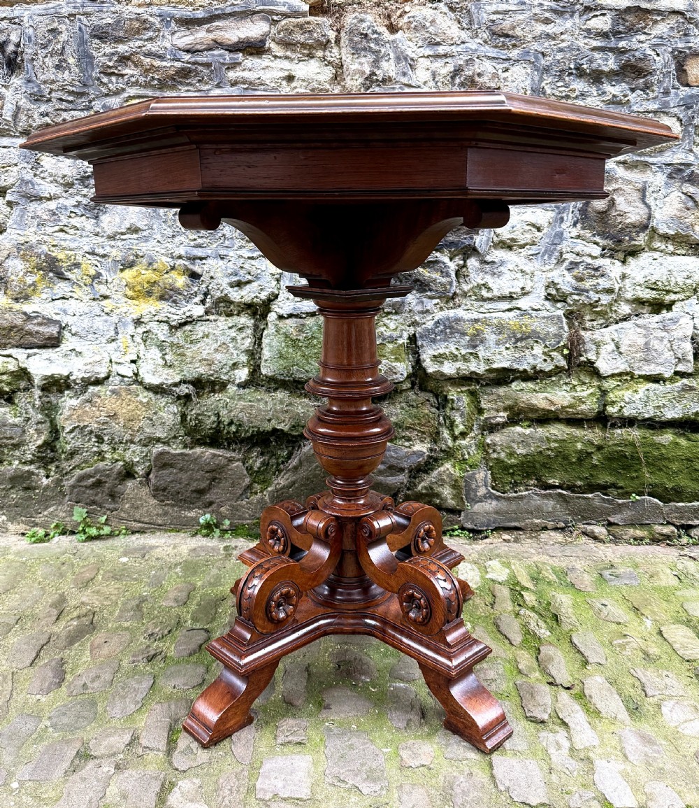 An octagonal mid-Victorian centre table crafted from walnut with a veneered top, turned pedestal stem, and carved four-legged scroll base. View II