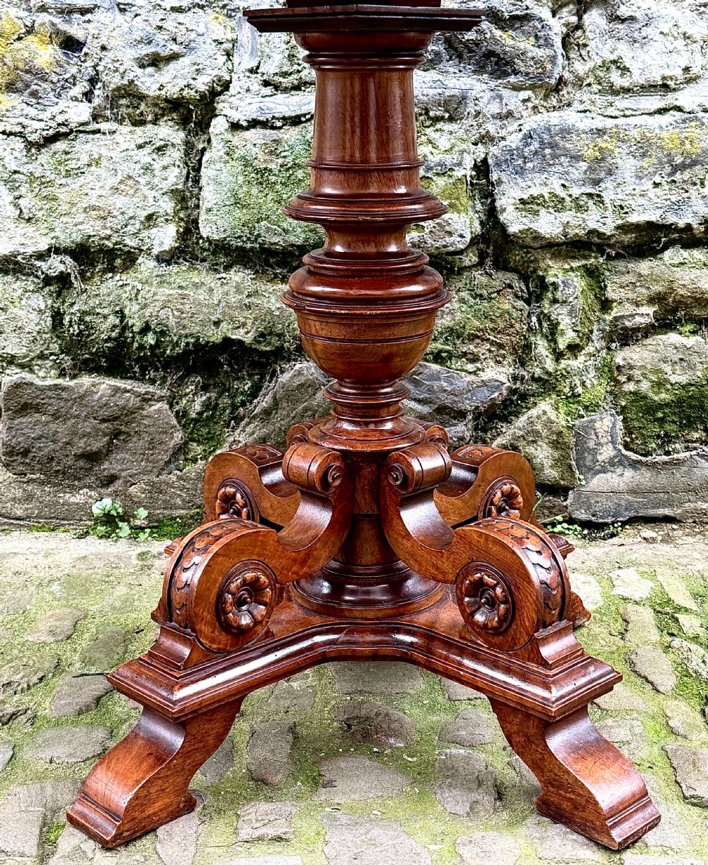 An octagonal mid-Victorian centre table crafted from walnut with a veneered top, turned pedestal stem, and carved four-legged scroll base. View III