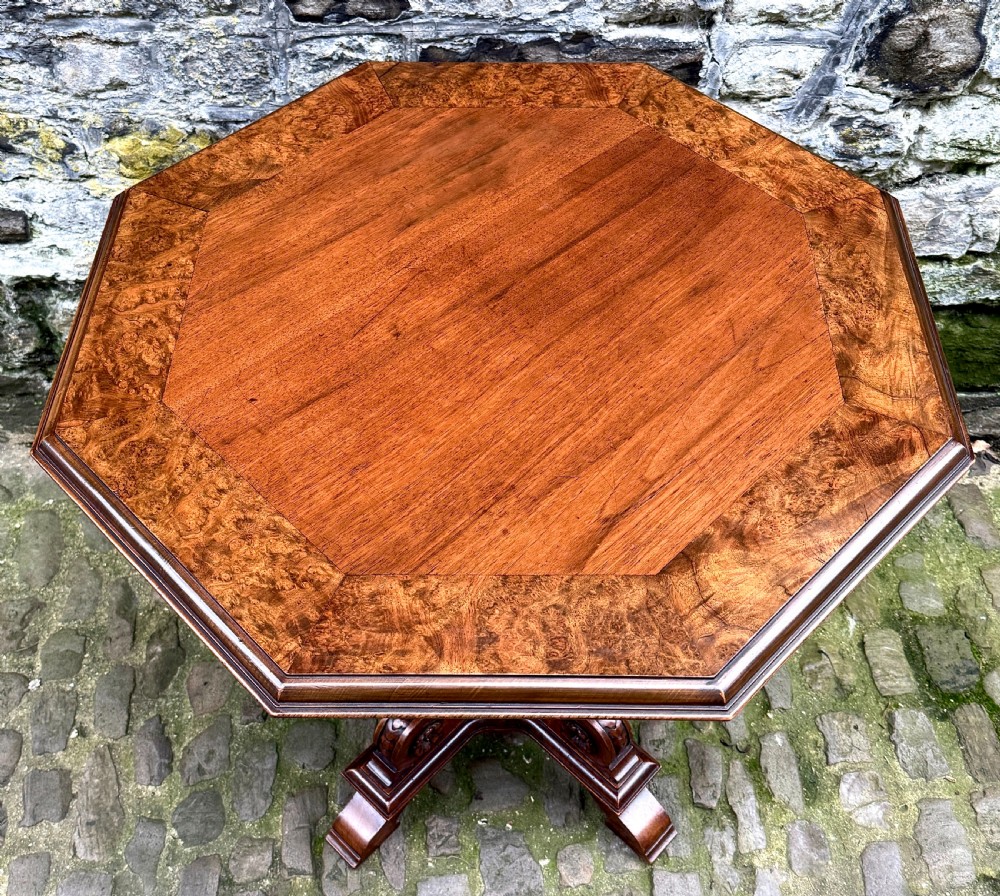An octagonal mid-Victorian centre table crafted from walnut with a veneered top, turned pedestal stem, and carved four-legged scroll base. View IV