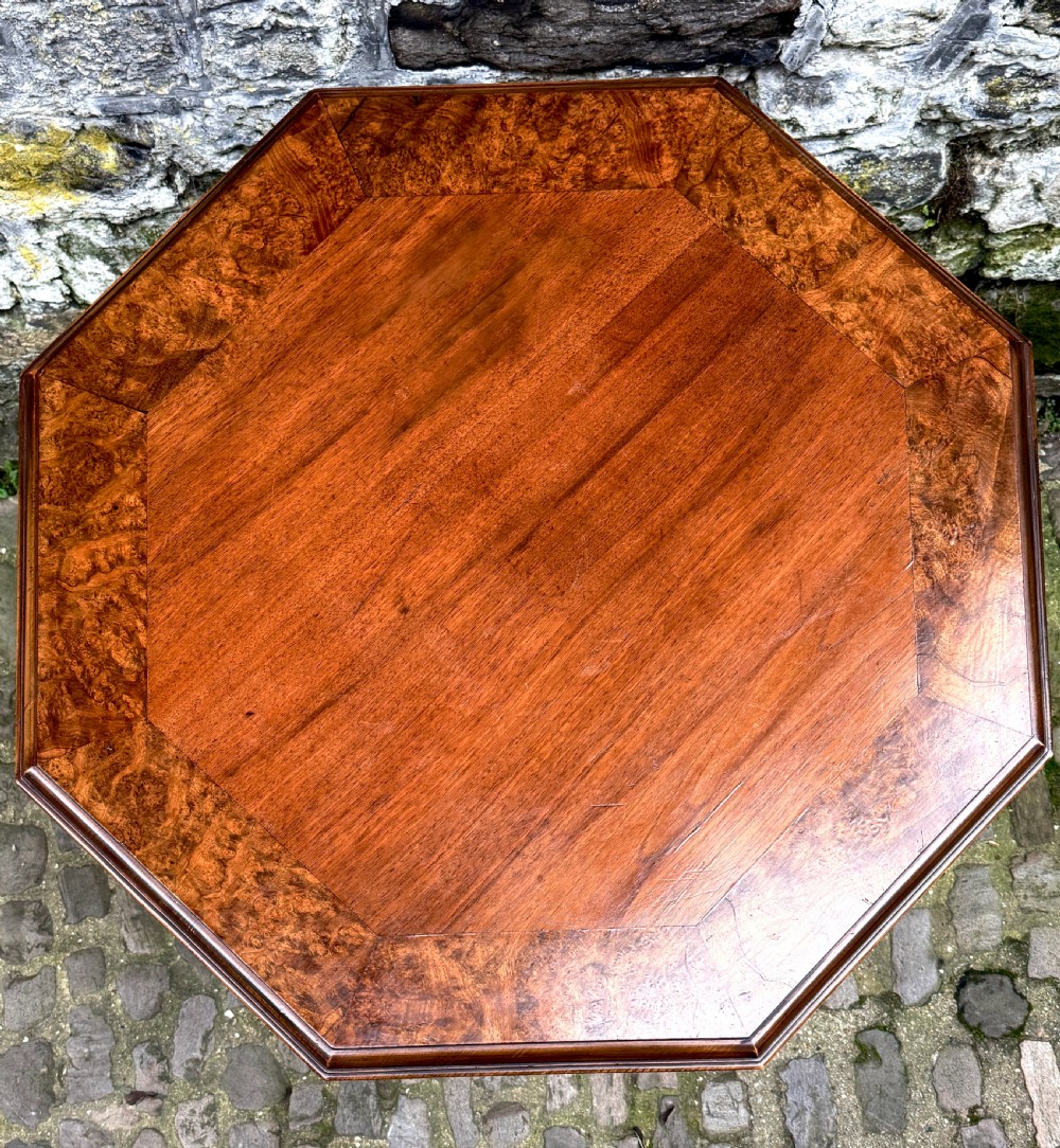 An octagonal mid-Victorian centre table crafted from walnut with a veneered top, turned pedestal stem, and carved four-legged scroll base. View V