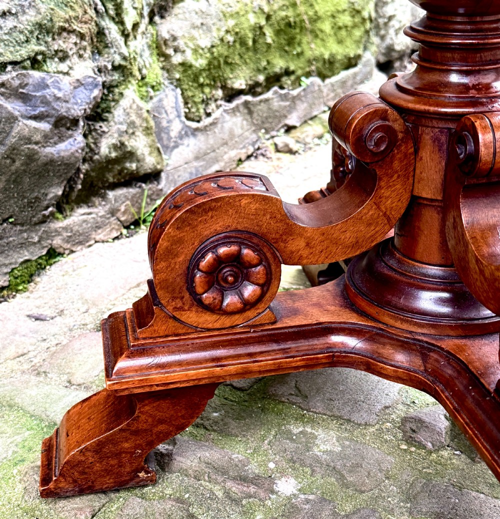 An octagonal mid-Victorian centre table crafted from walnut with a veneered top, turned pedestal stem, and carved four-legged scroll base. View VIII