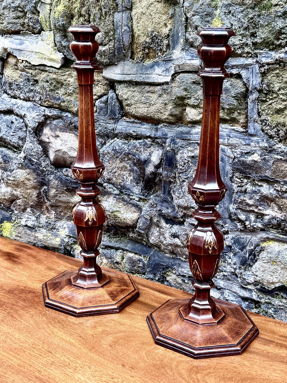 A pair of turned Adam style mahogany candlesticks featuring carved leaf detailing and octagonal bases. View II