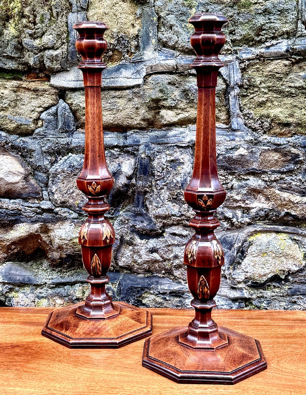 A pair of turned Adam style mahogany candlesticks featuring carved leaf detailing and octagonal bases. View III