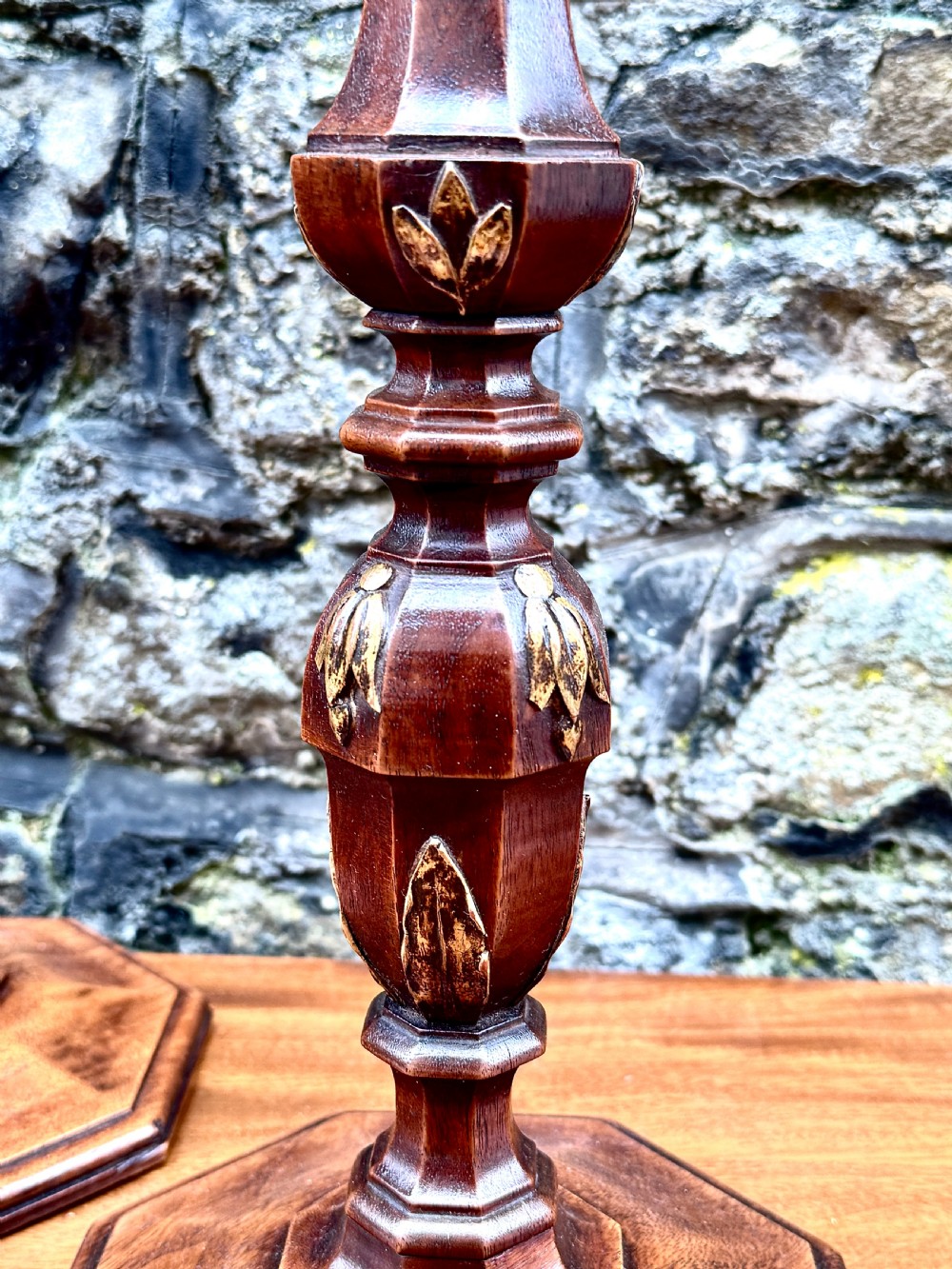 A pair of turned Adam style mahogany candlesticks featuring carved leaf detailing and octagonal bases. View IV