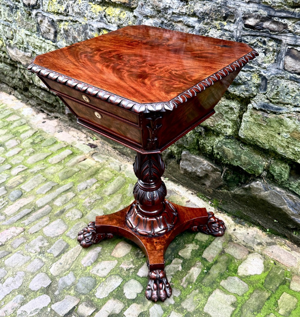 A William IV flame mahogany work table featuring a gadrooned top edge, two drawers with bone escutcheons, a carved pedestal stem, and a quadform base with claw feet. View III