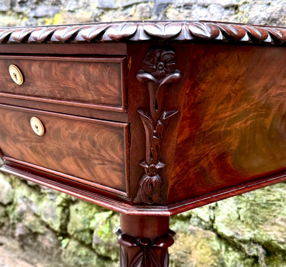 A William IV flame mahogany work table featuring a gadrooned top edge, two drawers with bone escutcheons, a carved pedestal stem, and a quadform base with claw feet. View IV