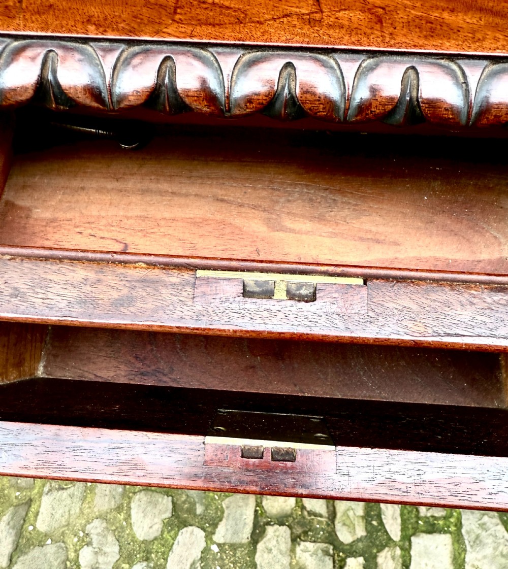 A William IV flame mahogany work table featuring a gadrooned top edge, two drawers with bone escutcheons, a carved pedestal stem, and a quadform base with claw feet. View X