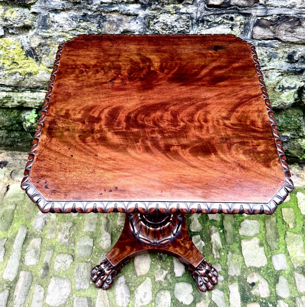 A William IV flame mahogany work table featuring a gadrooned top edge, two drawers with bone escutcheons, a carved pedestal stem, and a quadform base with claw feet. View XII