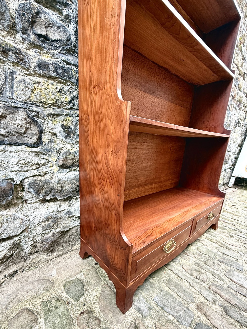 An early twentieth-century yew wood waterfall bookcase featuring four graduated open shelves above two drawers with brass handles. View VIII