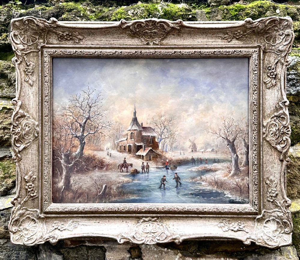 An early 20th-century Dutch winter landscape oil painting featuring figures skating on a frozen canal beside a church, housed within a swept frame with shell motifs.